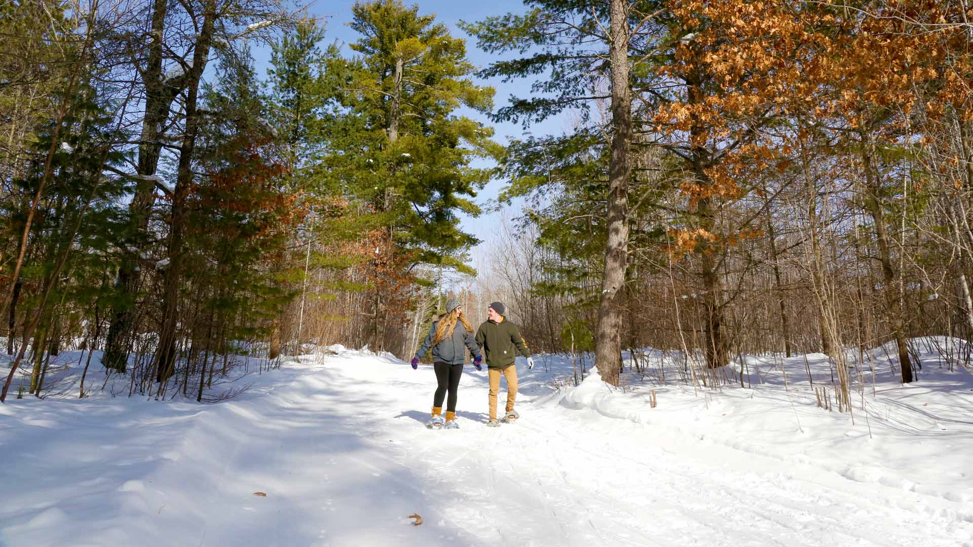 Couple hiking through the winter forest of Razorback Ridges Trail near Sayner, Wisconsin.