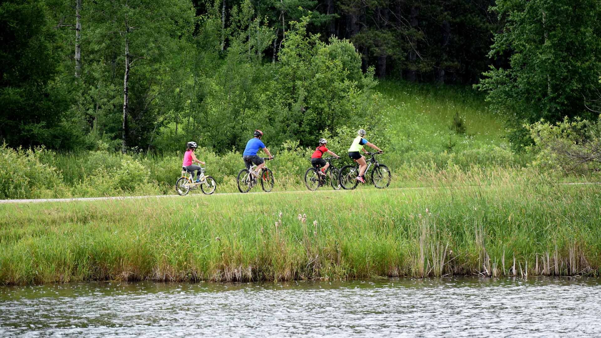 Group of cyclists riding on forest trail near water of Presque Isle Pomeroy Henry Trails in Vilas County, Wisconsin