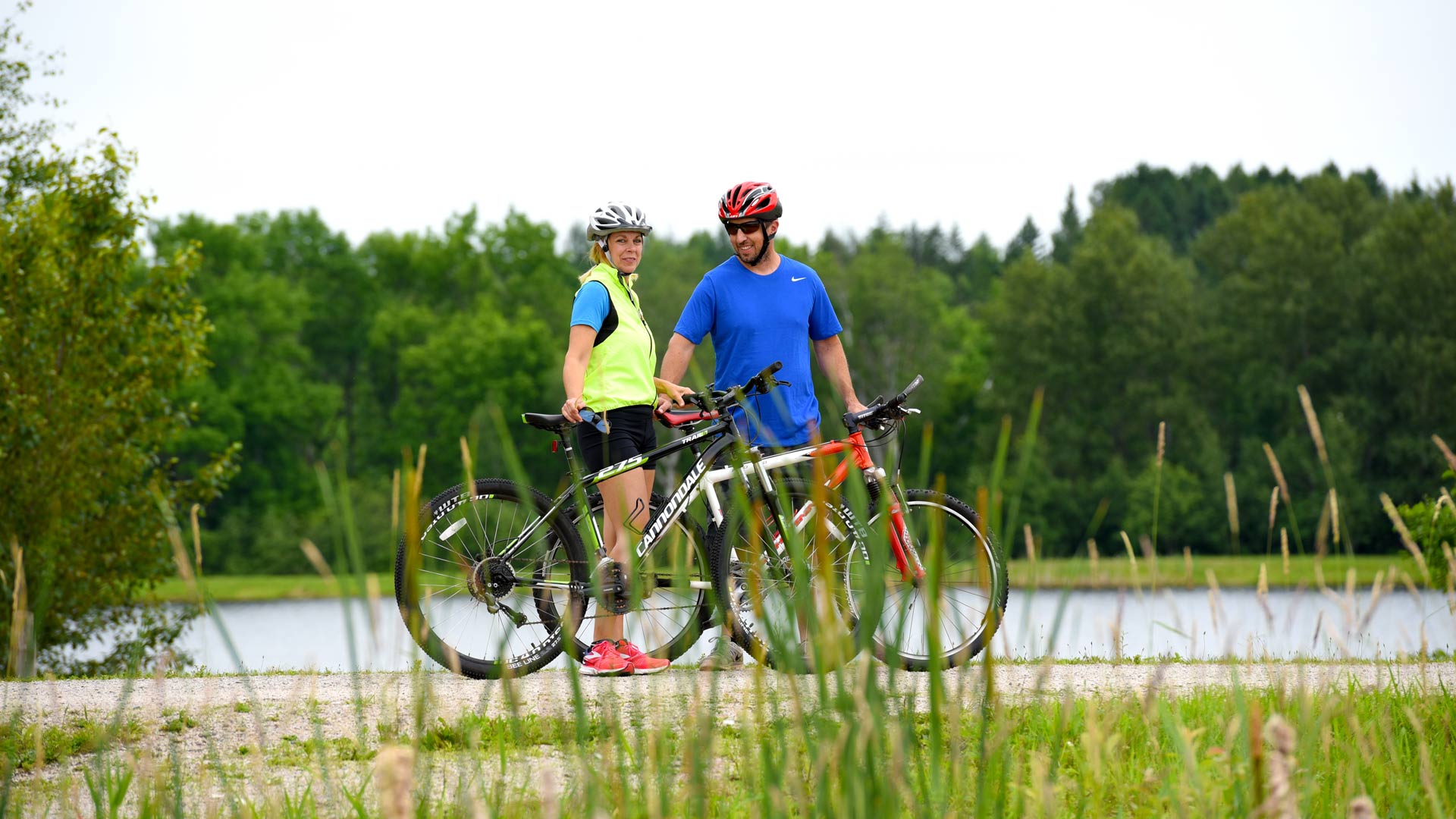 Cyclist couple in front of water and forest of Pipke Park Trail in Vilas County, Wisconsin