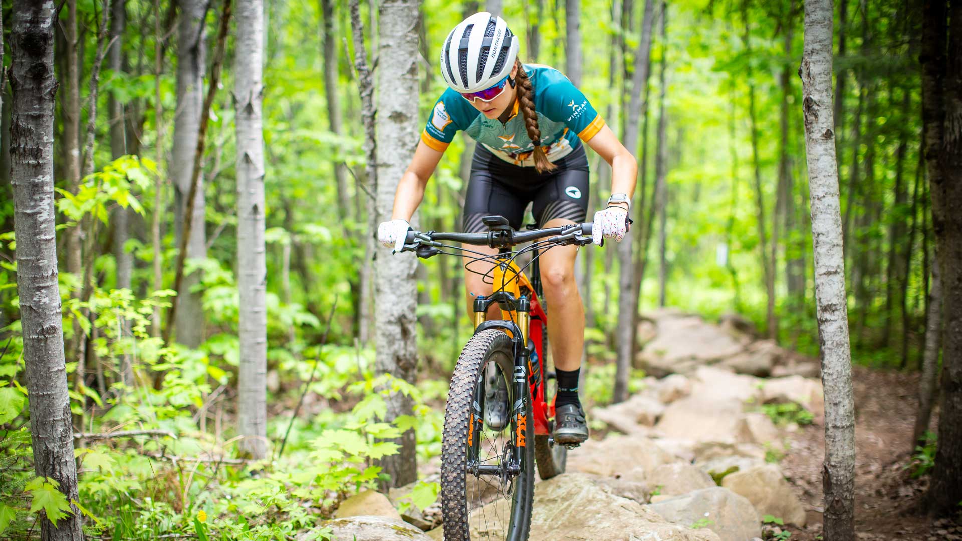 Girl wearing outdoor gear riding her mountain bike on WinMan trails