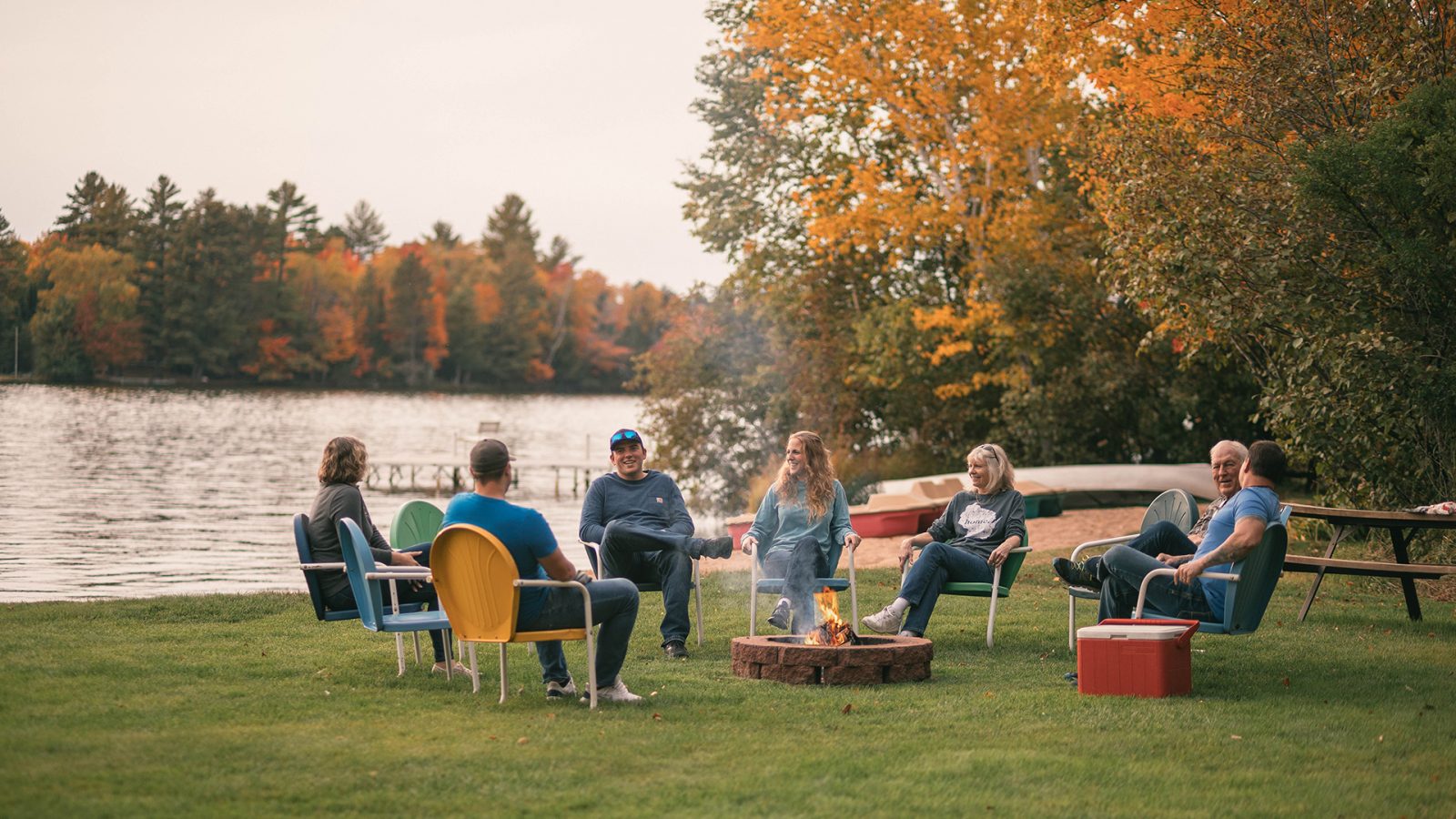 Family relaxing in chairs by the lake in the fall