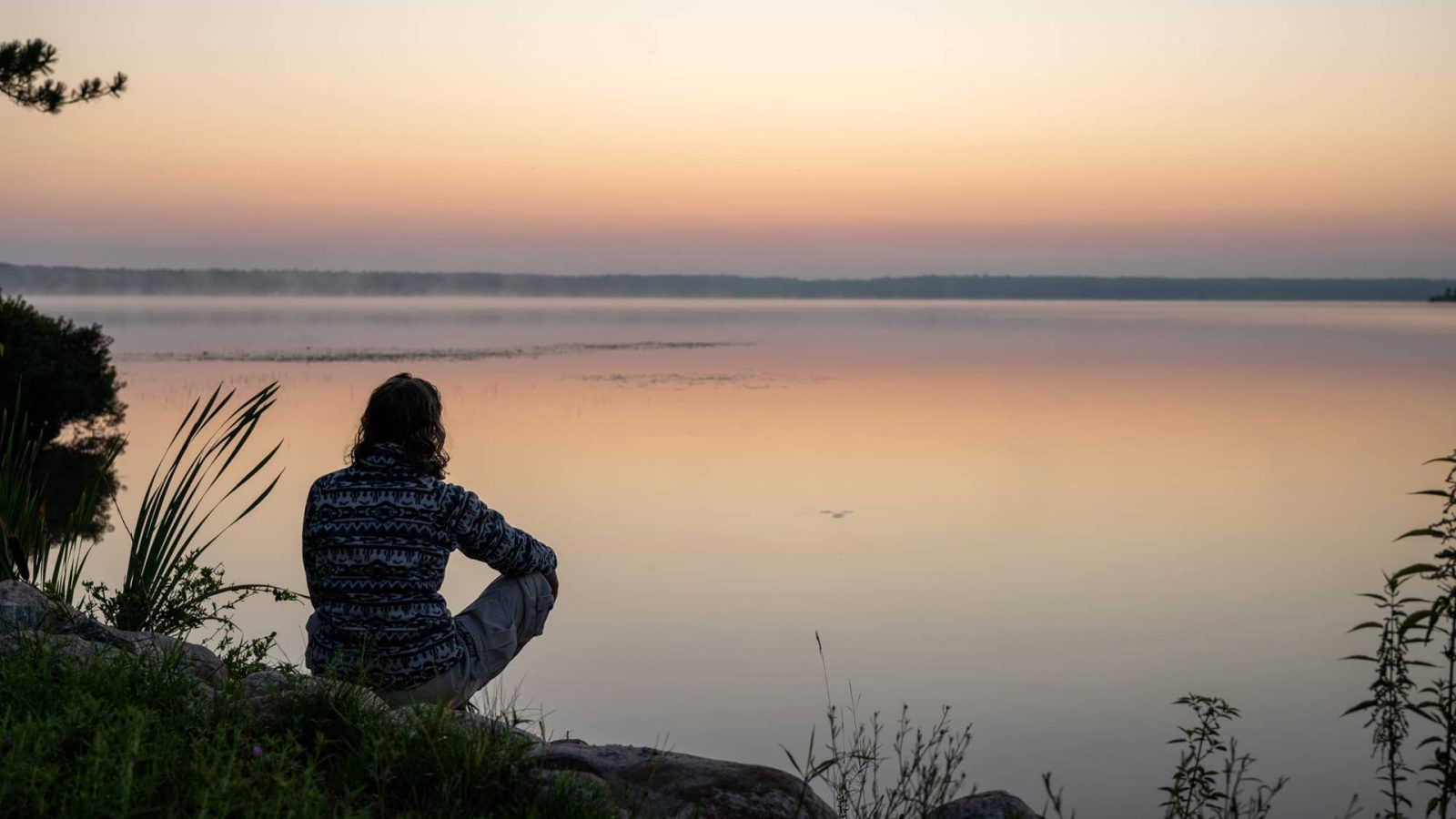 Woman sitting by lake at sunset St. Germain Vilas County WI