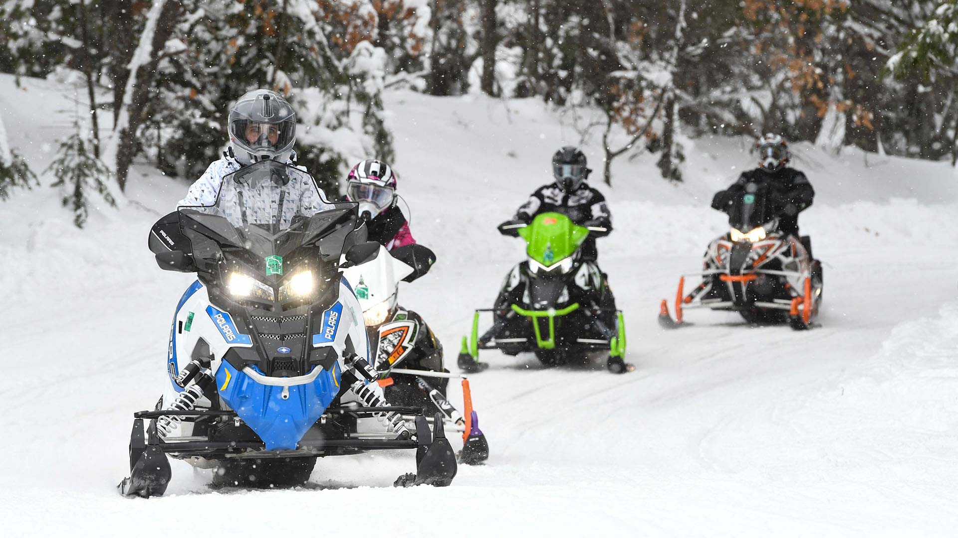 Group of snowmobilers riding by Dollar Lake