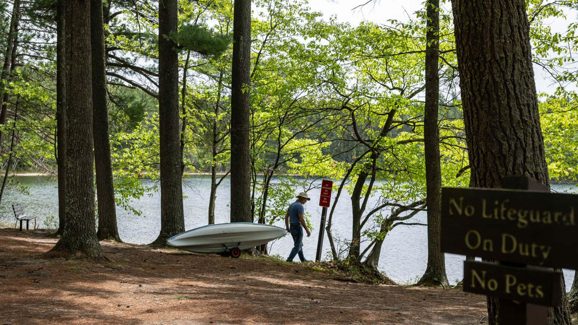 man walking a kayak to the water's edge at firefly lake