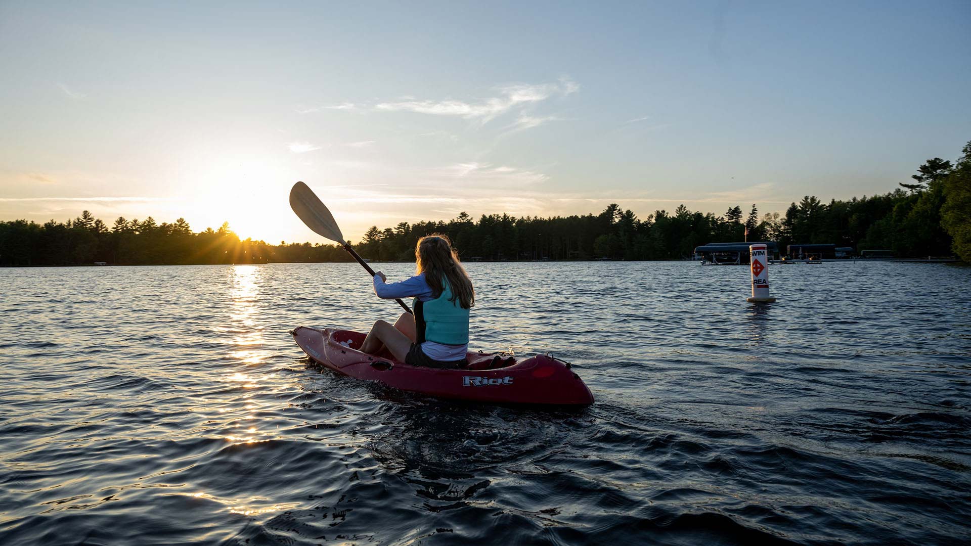 Girl kayaking in front of Last Resort in Eagle River during sunset