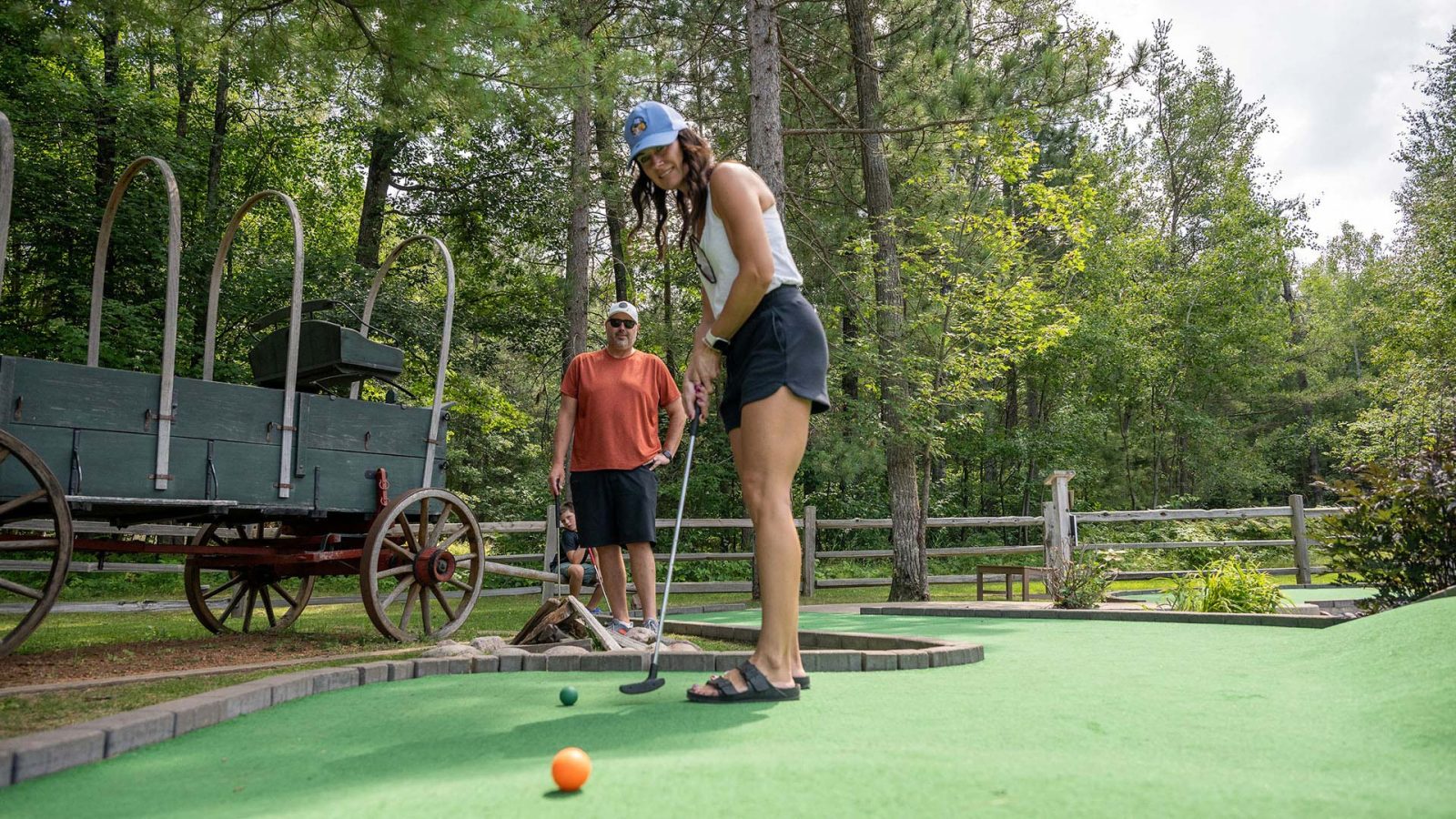 A women mini-putting as her husband looks on at Elmer's Fun Park