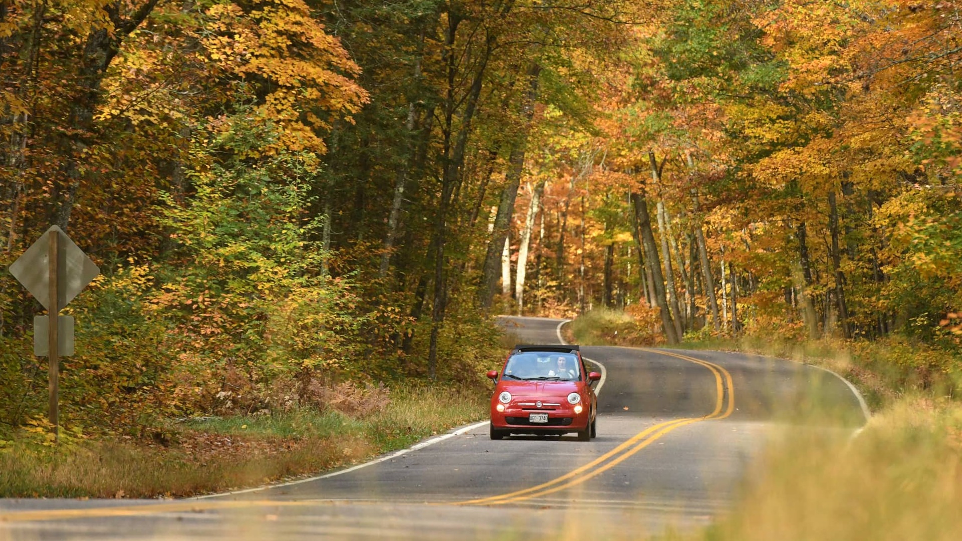 Car going for a scenic drive surrounded by fall colored foliage