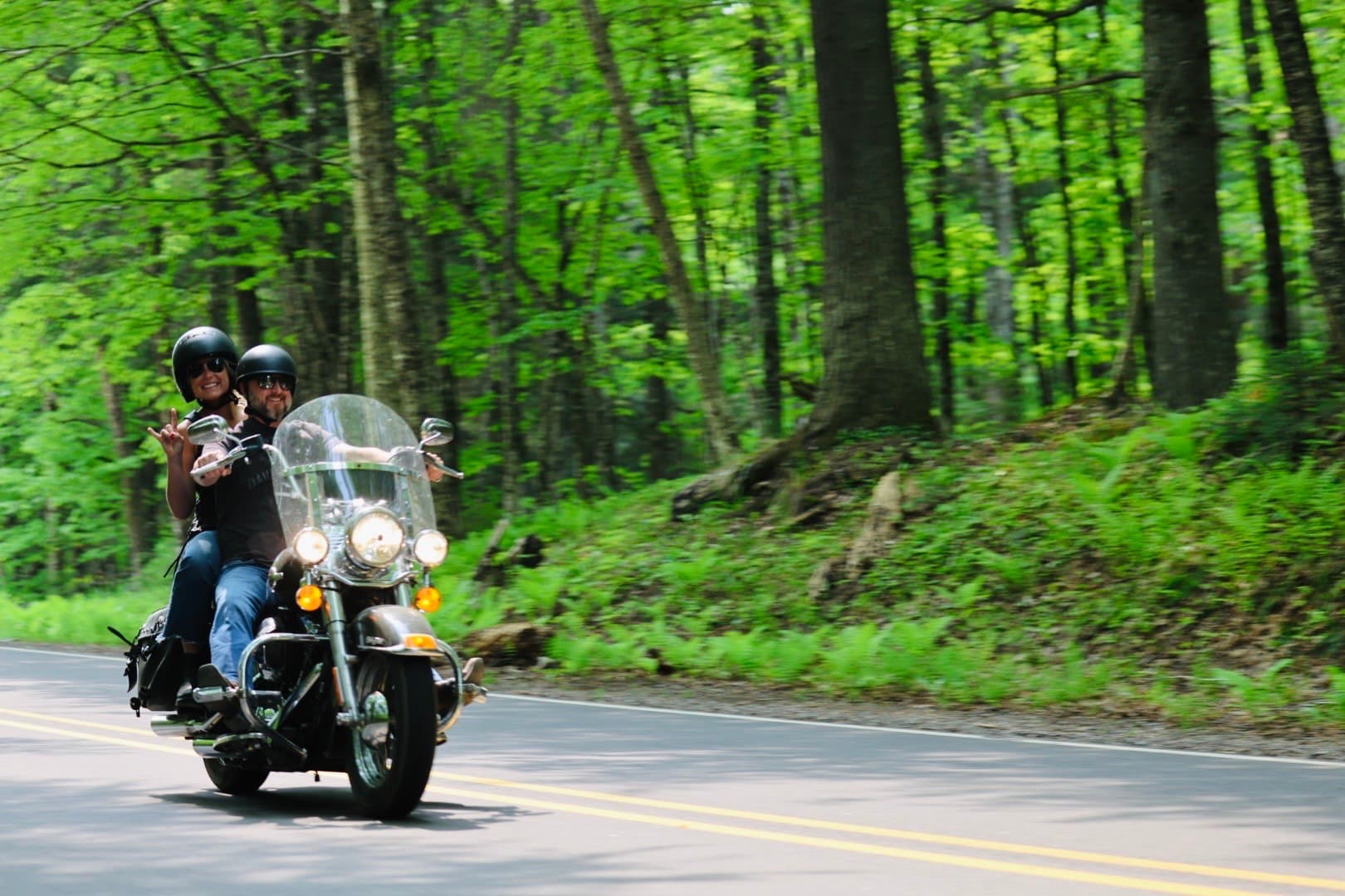 Couple riding motorcycle along a Vilas County Road lined by trees