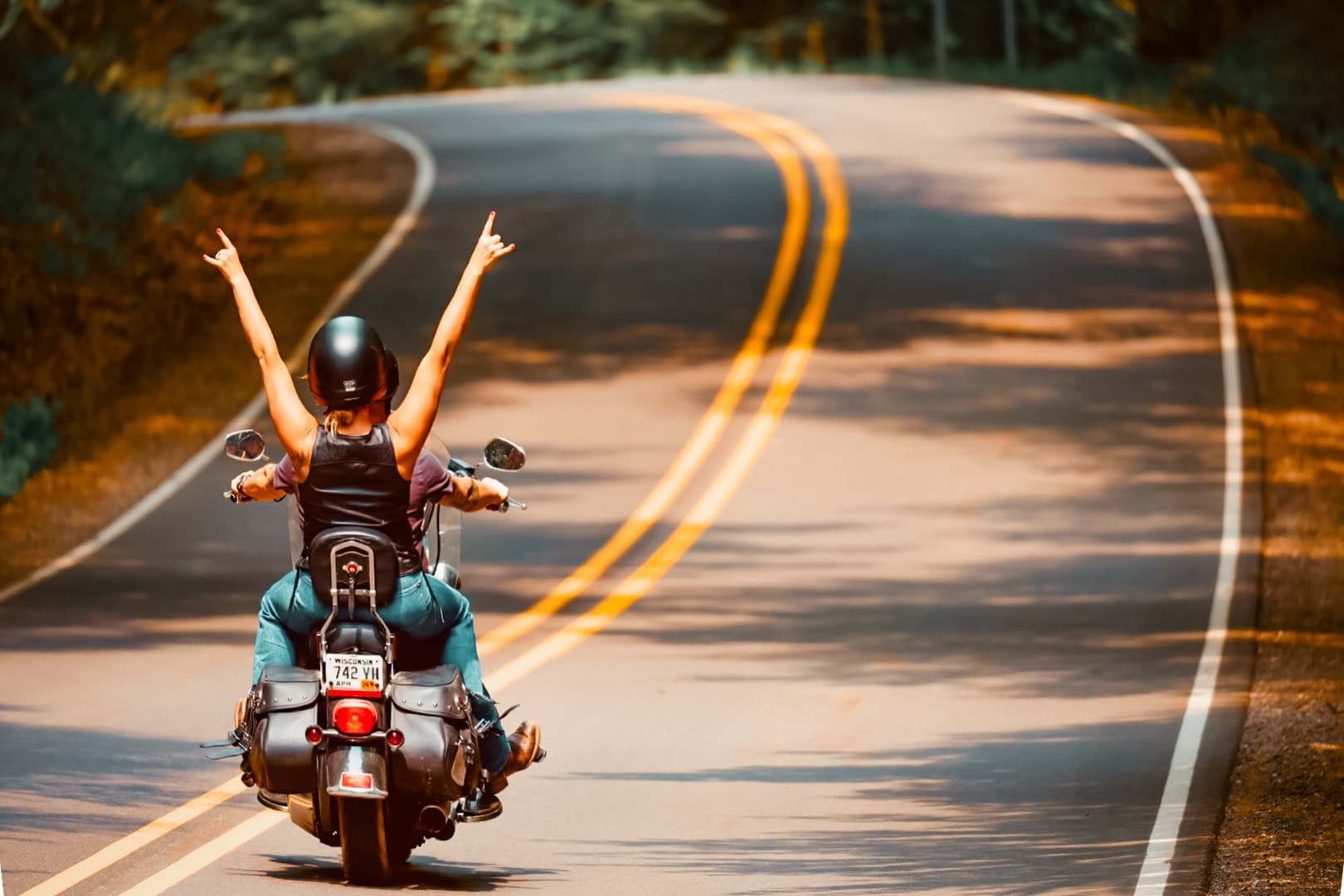 Couple riding motorcycle along a Vilas County Road lined by trees