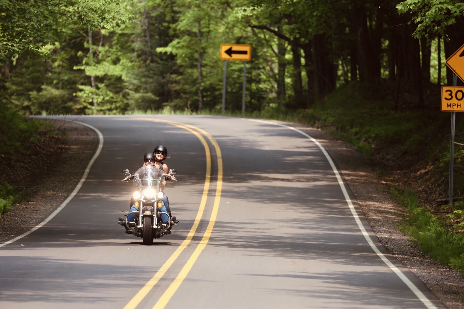 Couple riding motorcycle along a Vilas County Road lined by trees