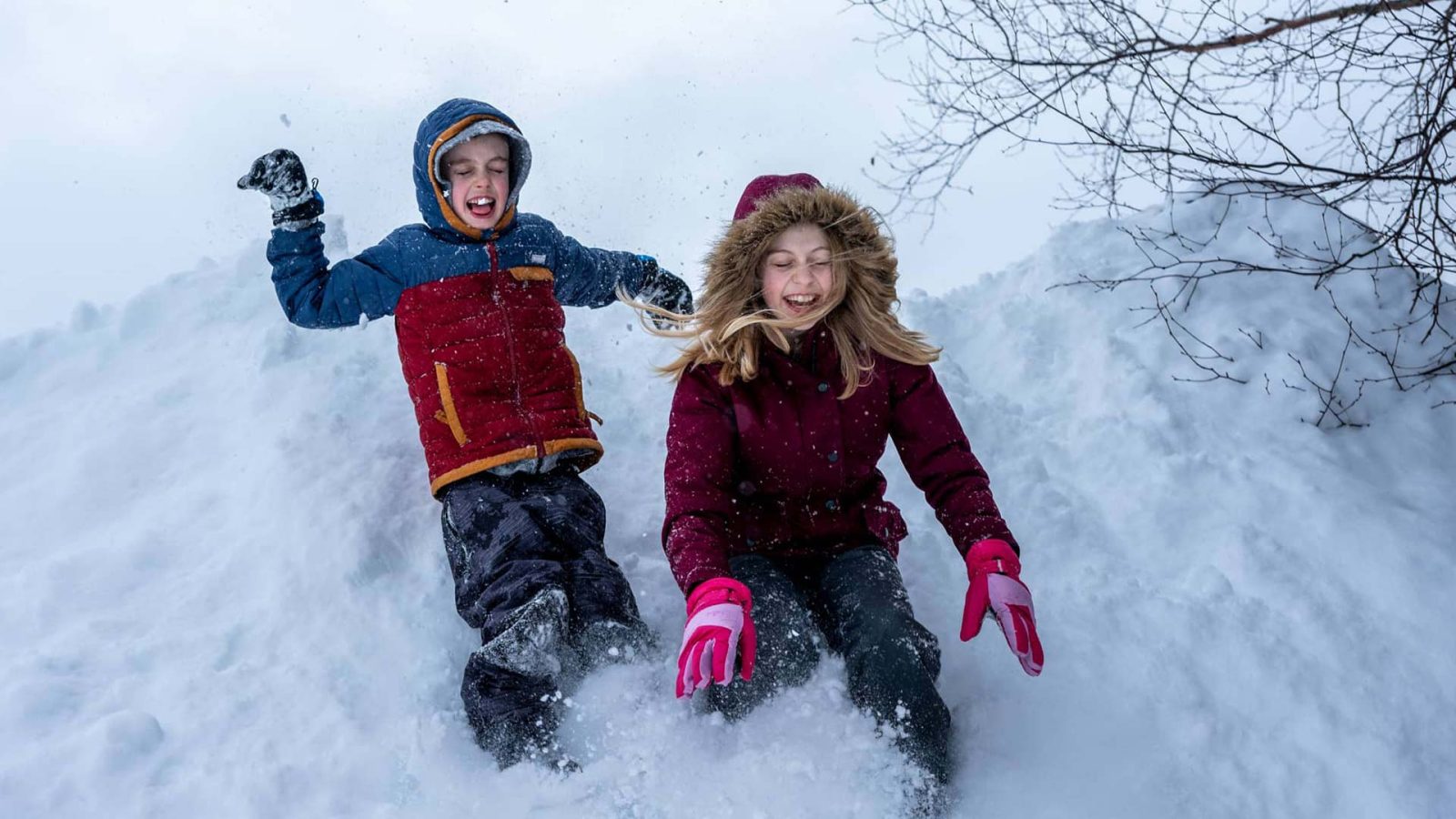 Boy and girl sliding down snow hill at Conover Town Park in Vilas County Wisconsin