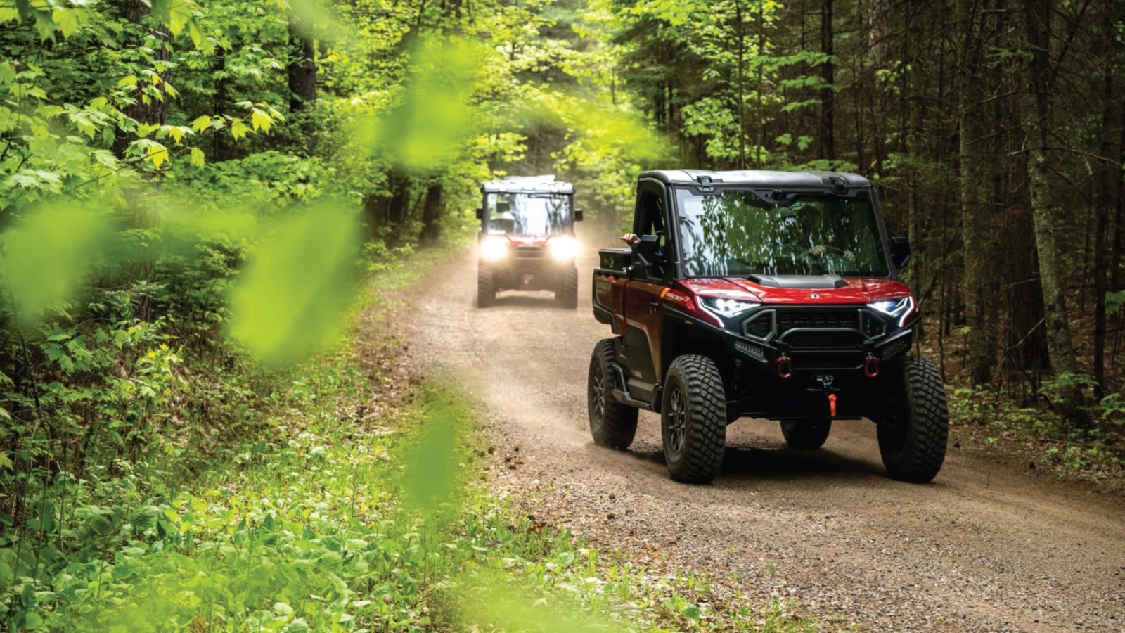 Two UTVs riding on a trail in the woods in Vilas County Wisconsin